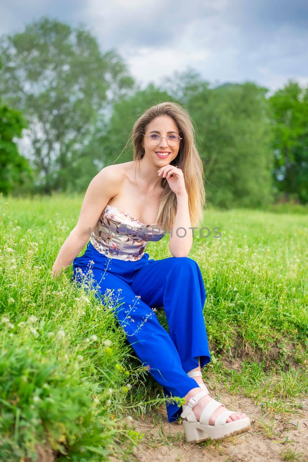 young woman with glasses sitting on a meadow