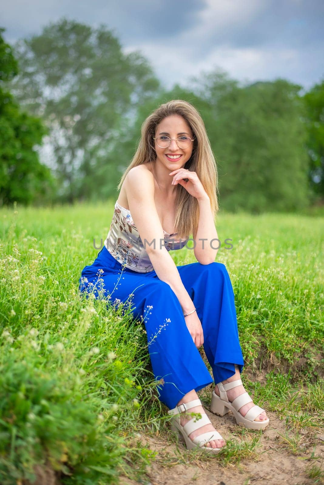 young woman with glasses sitting on a meadow