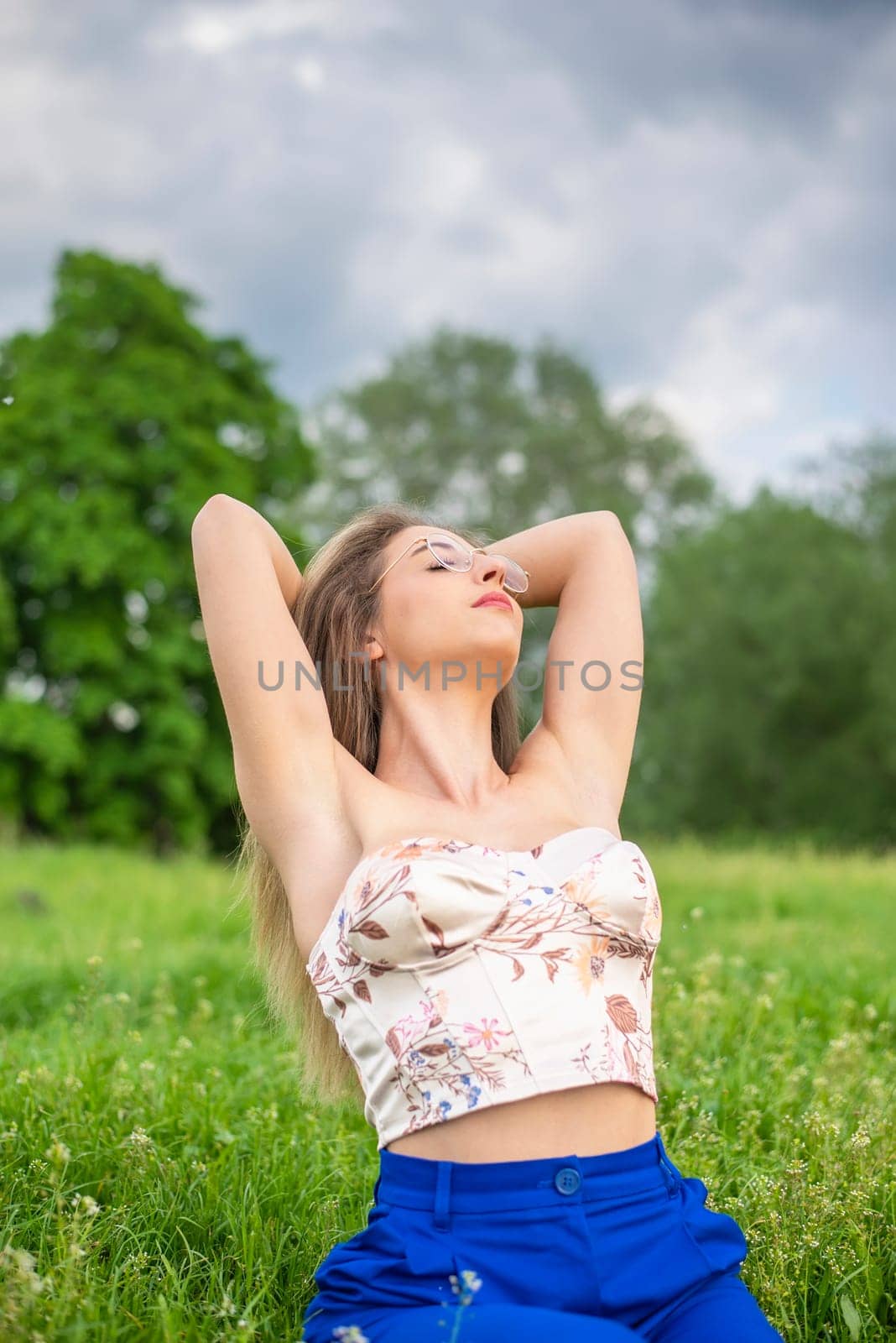young woman with glasses sitting on a meadow
