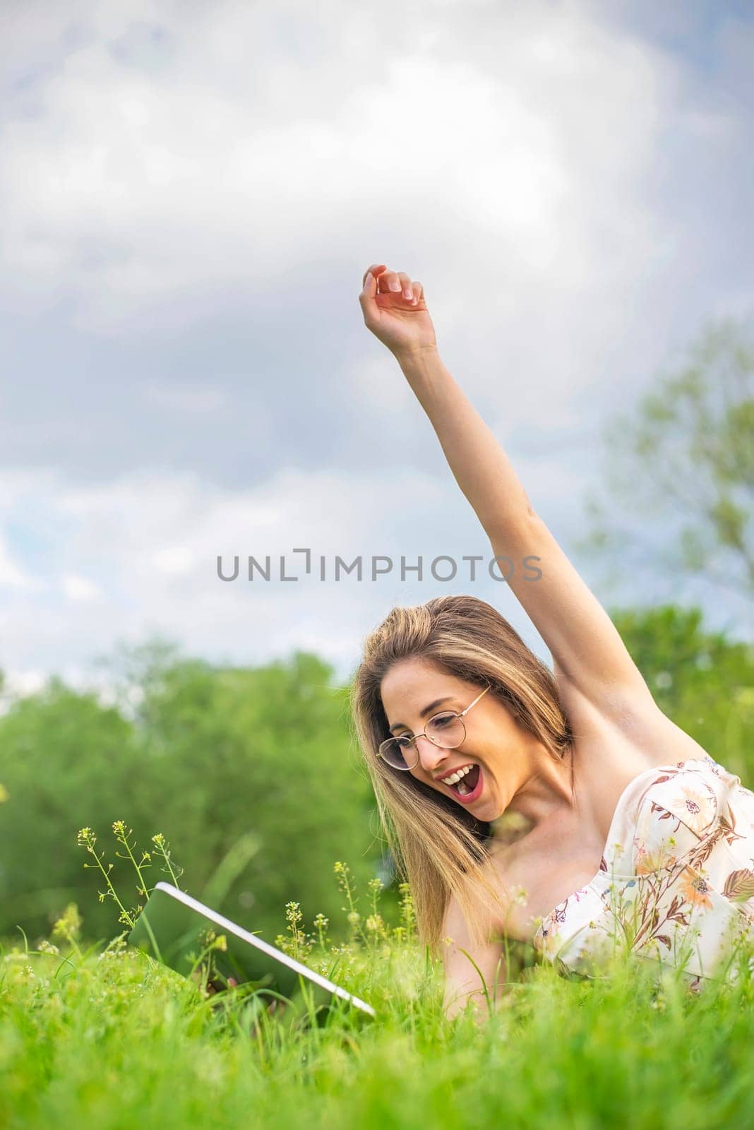 happy young woman with digital tablet lying on a meadow