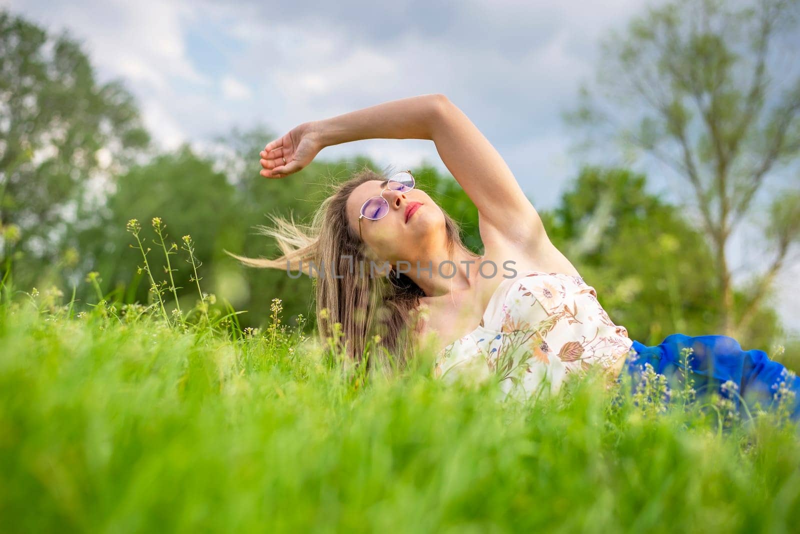 young woman with glasses lying on a meadow