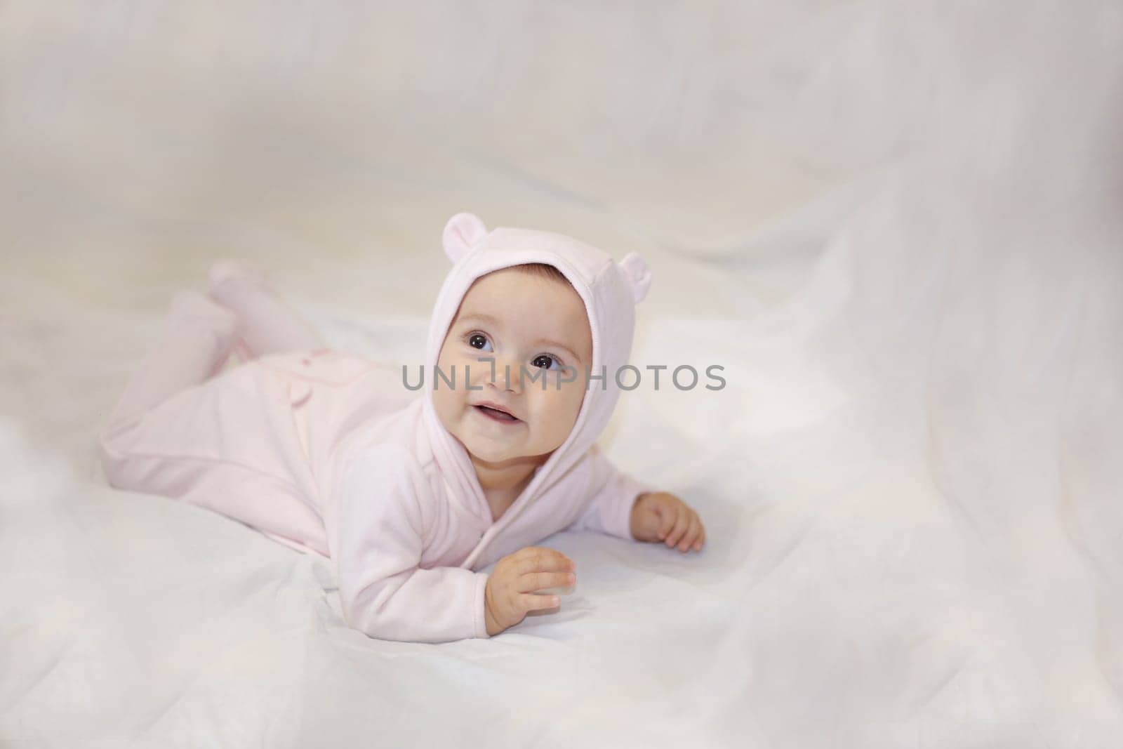 Lying smiling child in a bear costume on a light background.View from above