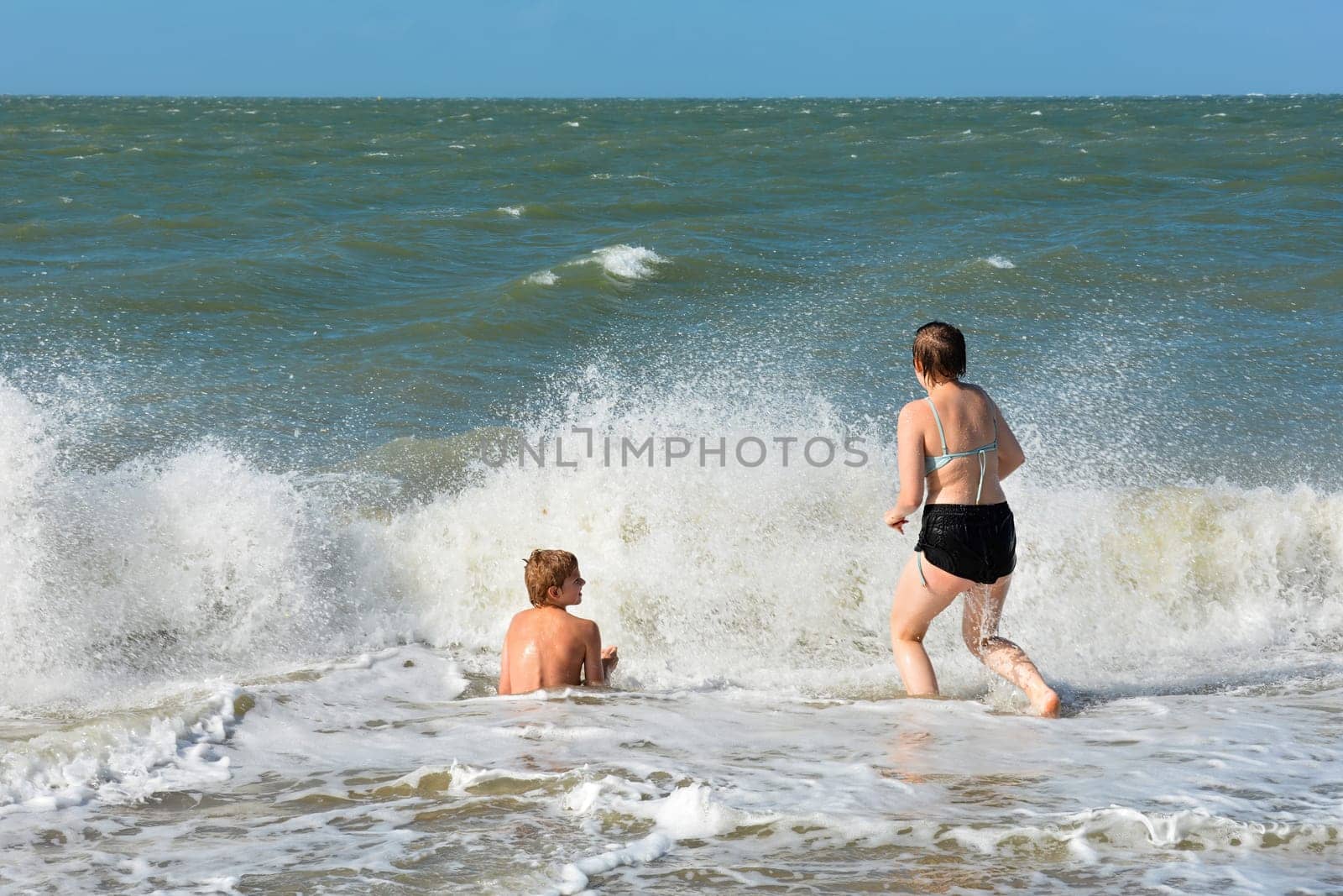 A boy and a teenage girl have fun in the waves on the sea beach,A boy and a teenage girl have fun in the waves on the sea beach