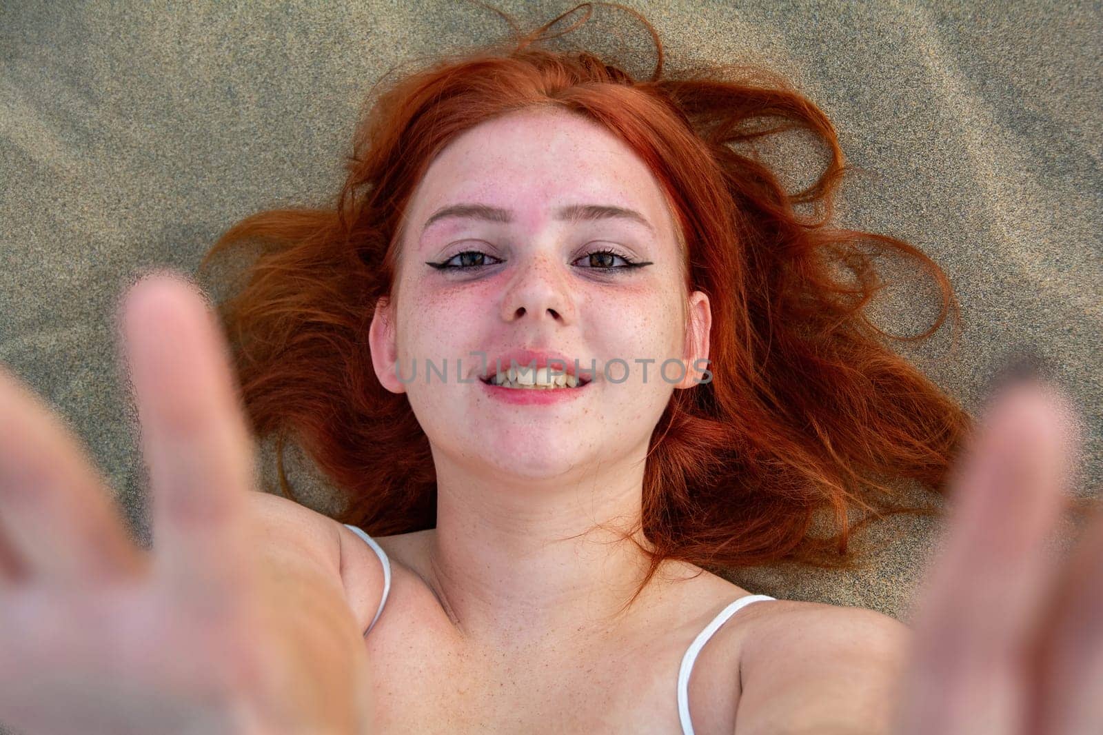 A young girl lies in the sand dunes in a white dress