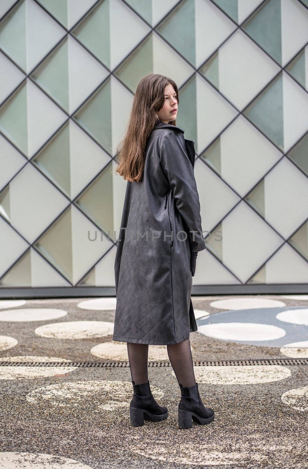 confident young woman with long black coat in the city