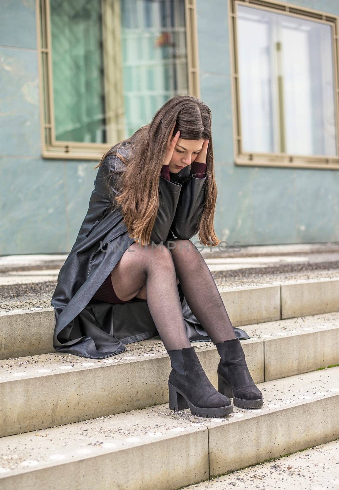 pensive young woman sitting on the stairs