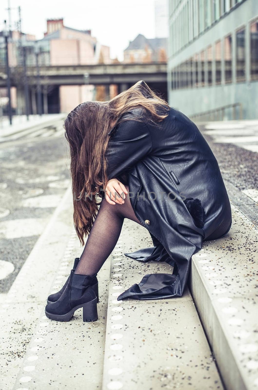 pensive young woman sitting on the stairs
