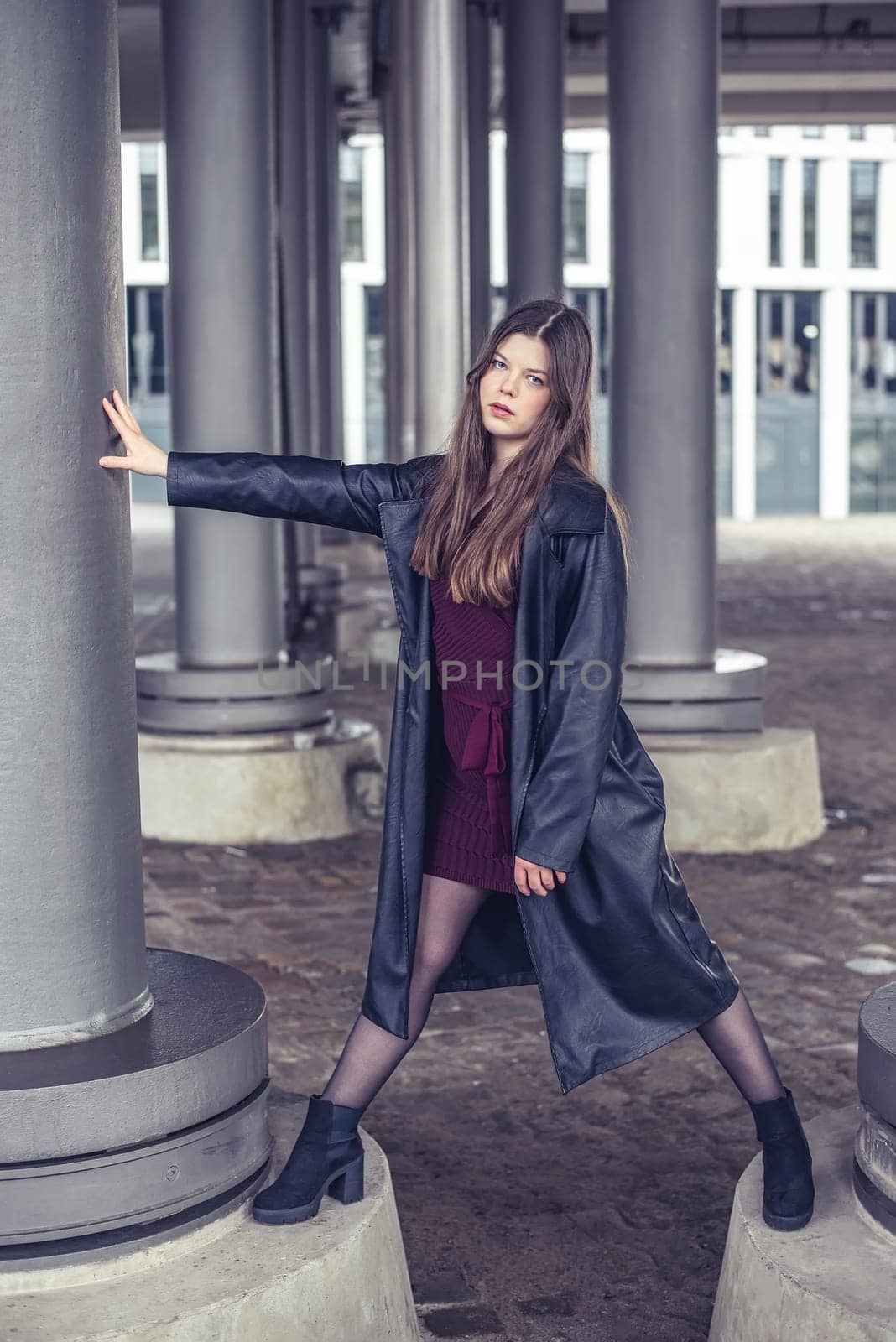 confident young woman with long black coat in the city