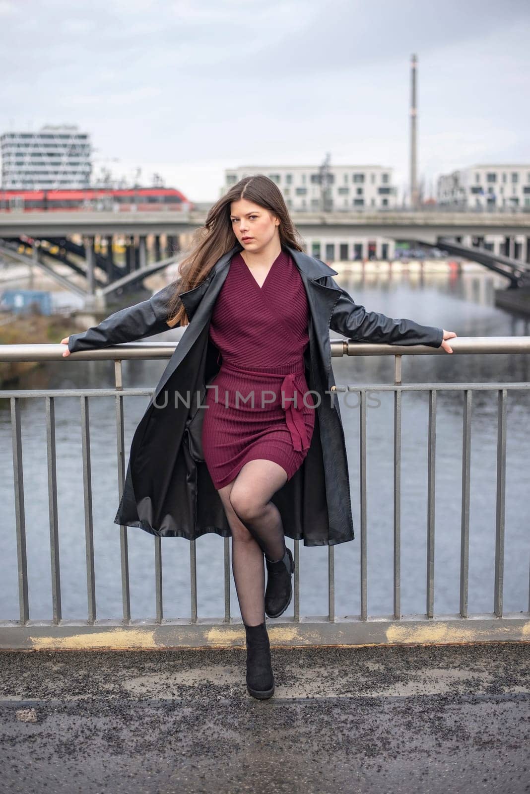 relaxed young woman wearing a black coat standing on a bridge