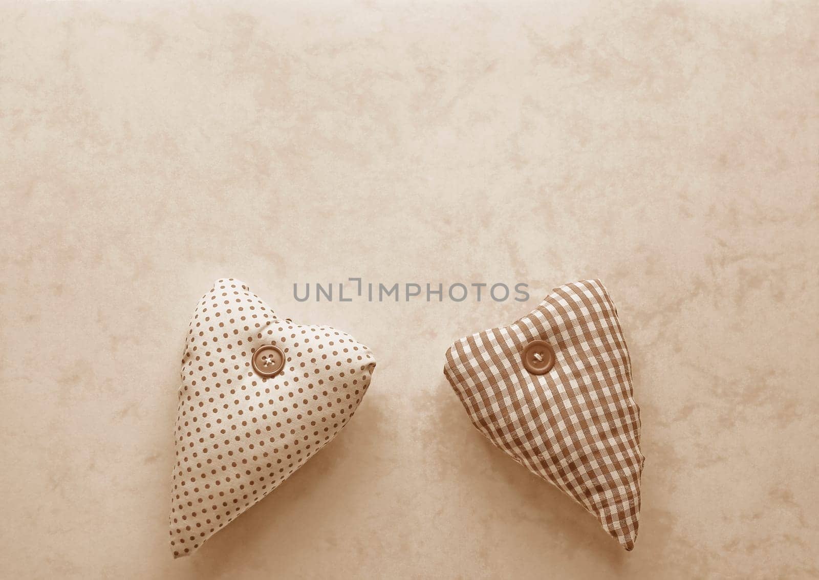 Two fabric hearts in Peach Fuzz on a paper background