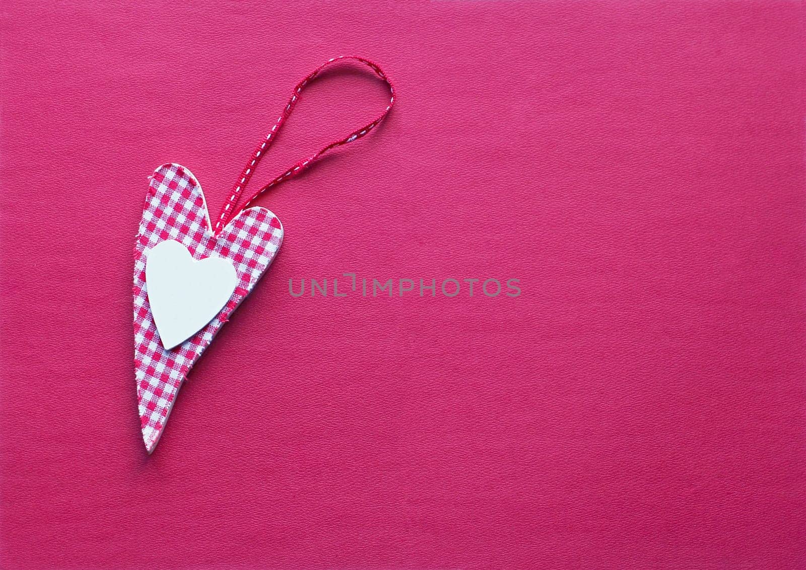 A fabric heart in pink on a paper background