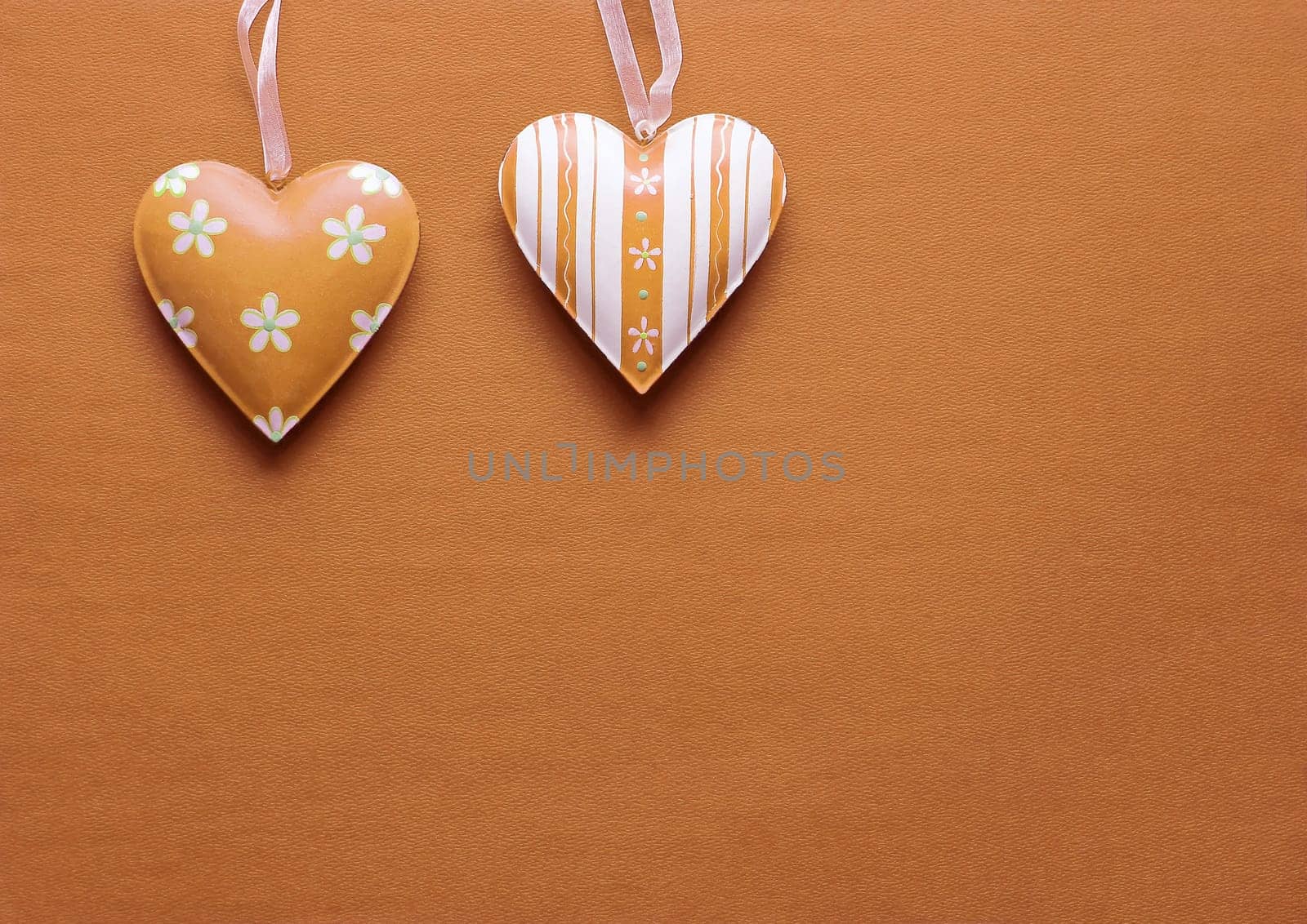 Two metal hearts in Peach Fuzz on a paper background