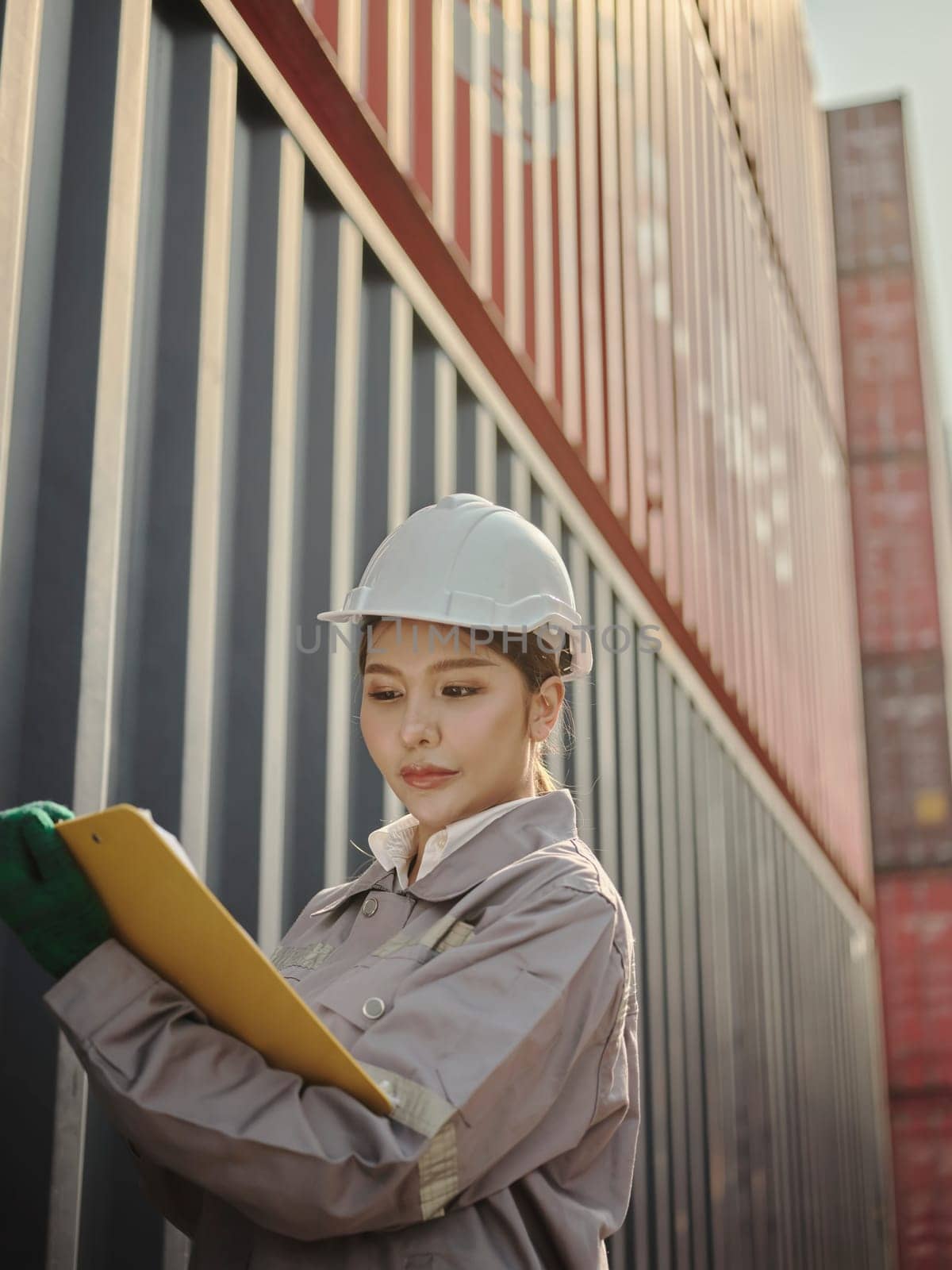 Asian woman engineer working in container port terminal.   process orders and product at warehouse logistic in cargo for import export