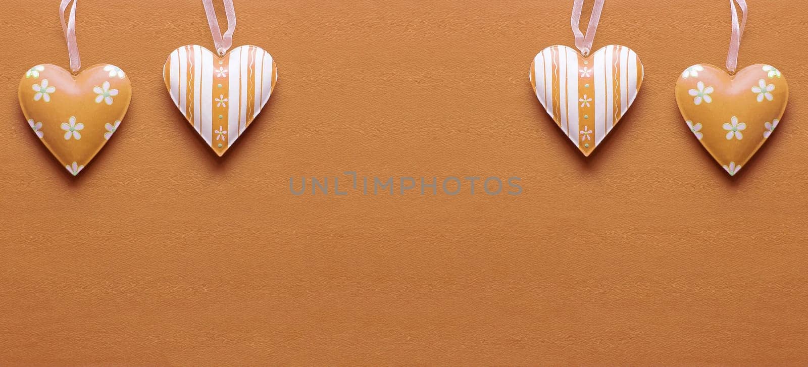 Two metal hearts in Peach Fuzz on a paper background
