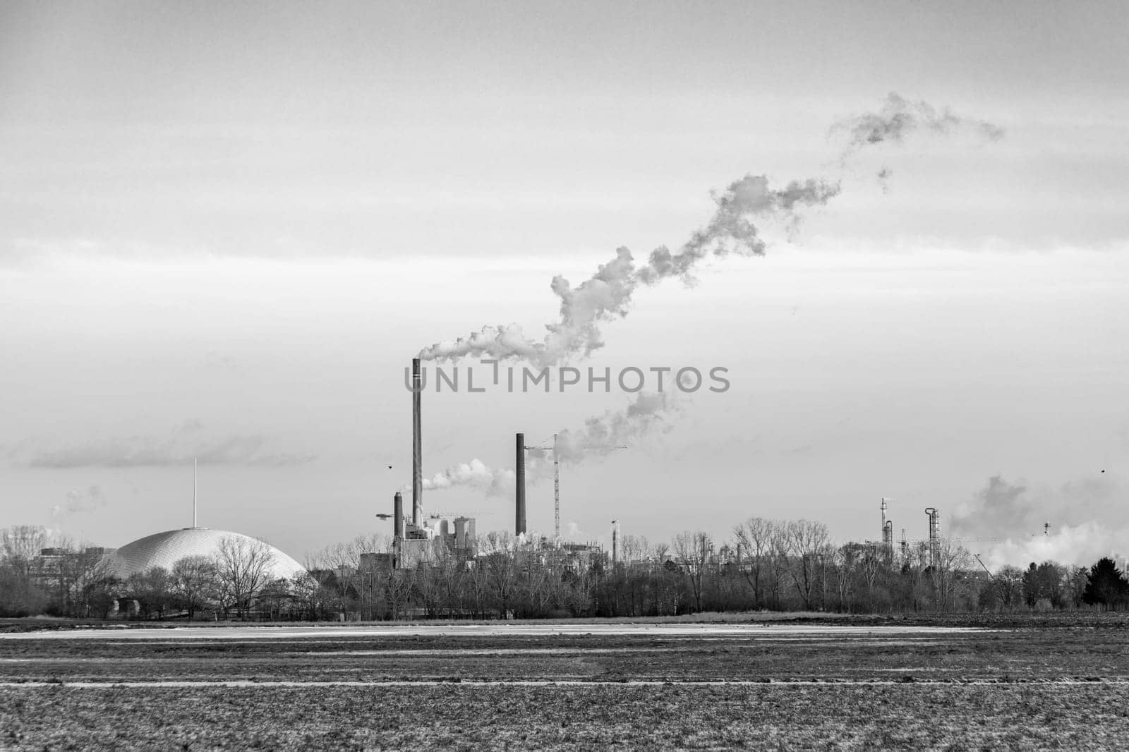 industry complex in Frankfurt in late evening with  fields and smoking chimney in winter