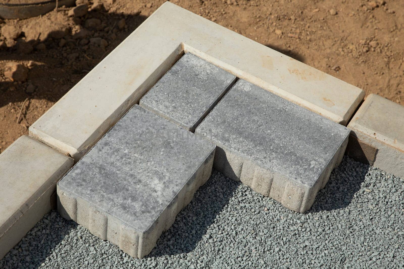 Laying gray concrete paving slabs in the courtyard of the house on a sandy foundation.