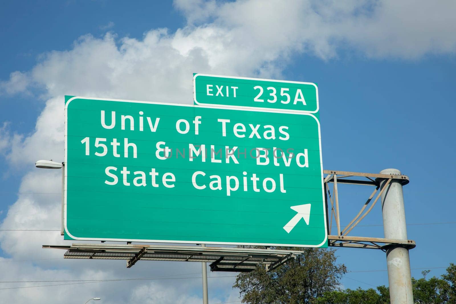 exit University of Texas and State Capitol in Austin from  interstate 35 in afternoon sun with clouds