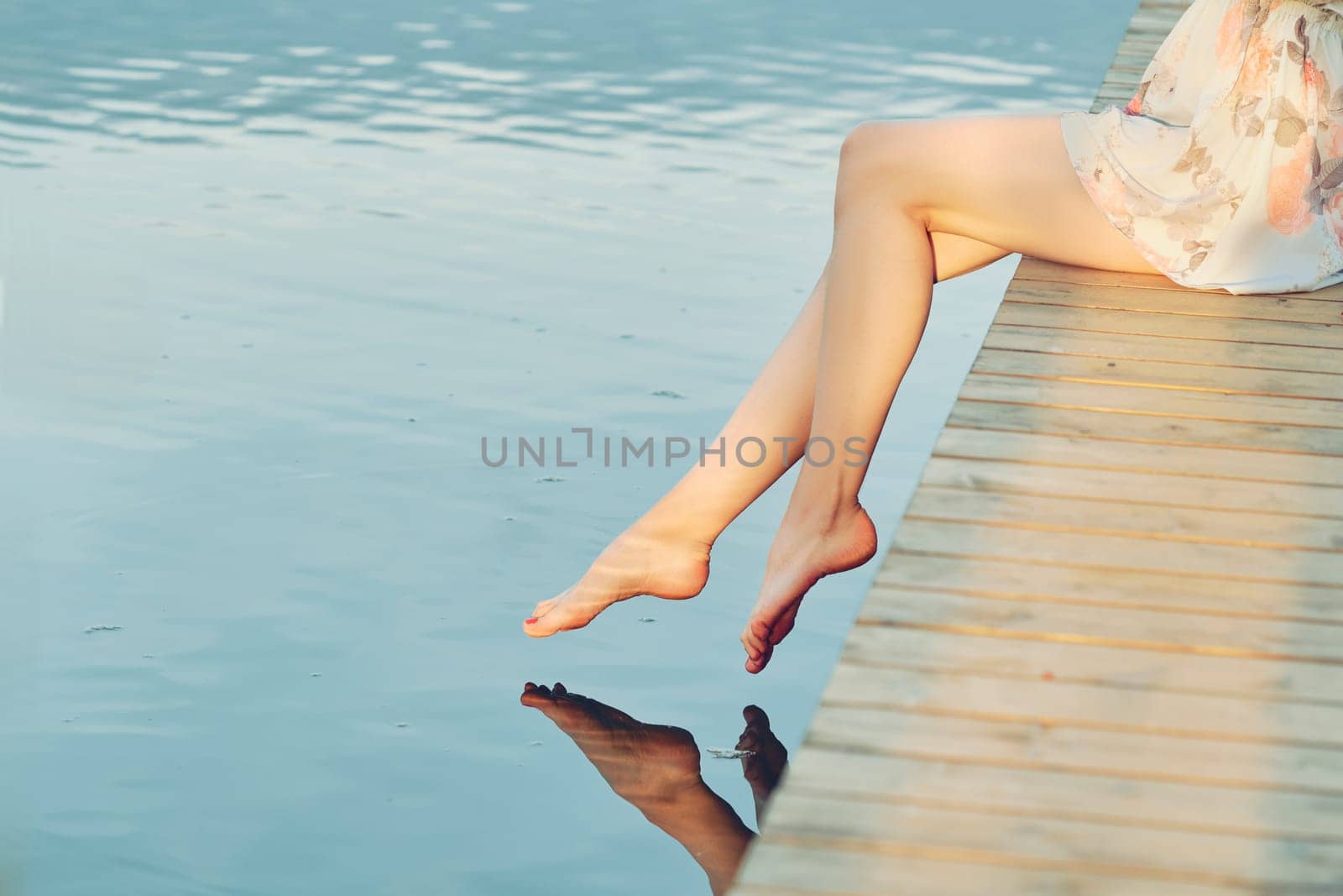 Barefoot female feet above calm water