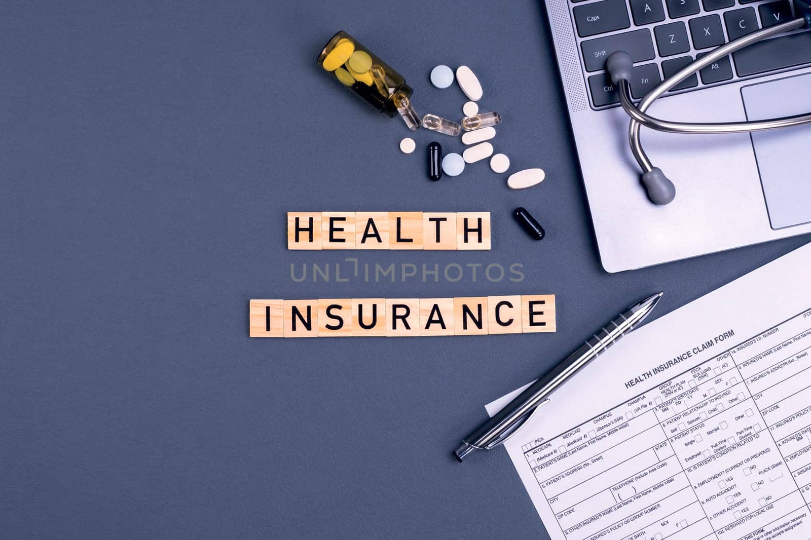 Health insurance form claim with laptop, stethoscope and pills on table. Medical insurance, health risk, pay for the healthcare concept.