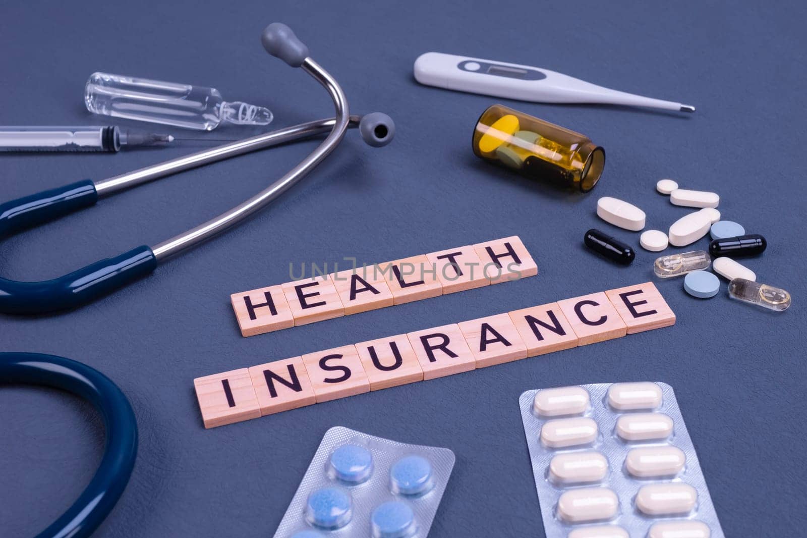 Health insurance text with stethoscope and pills on table. Medical insurance, health risk, pay for the healthcare concept.