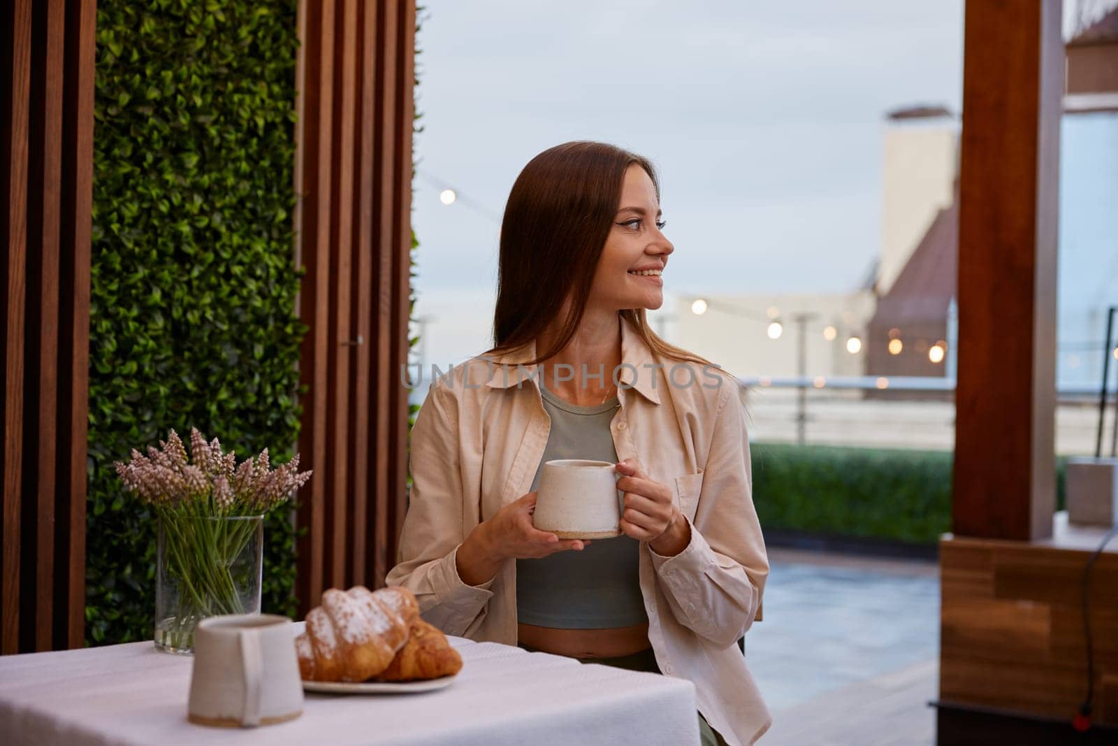 Young attractive woman sitting at table drinking coffee in cafe. Freelance occupation and remote work enjoyment