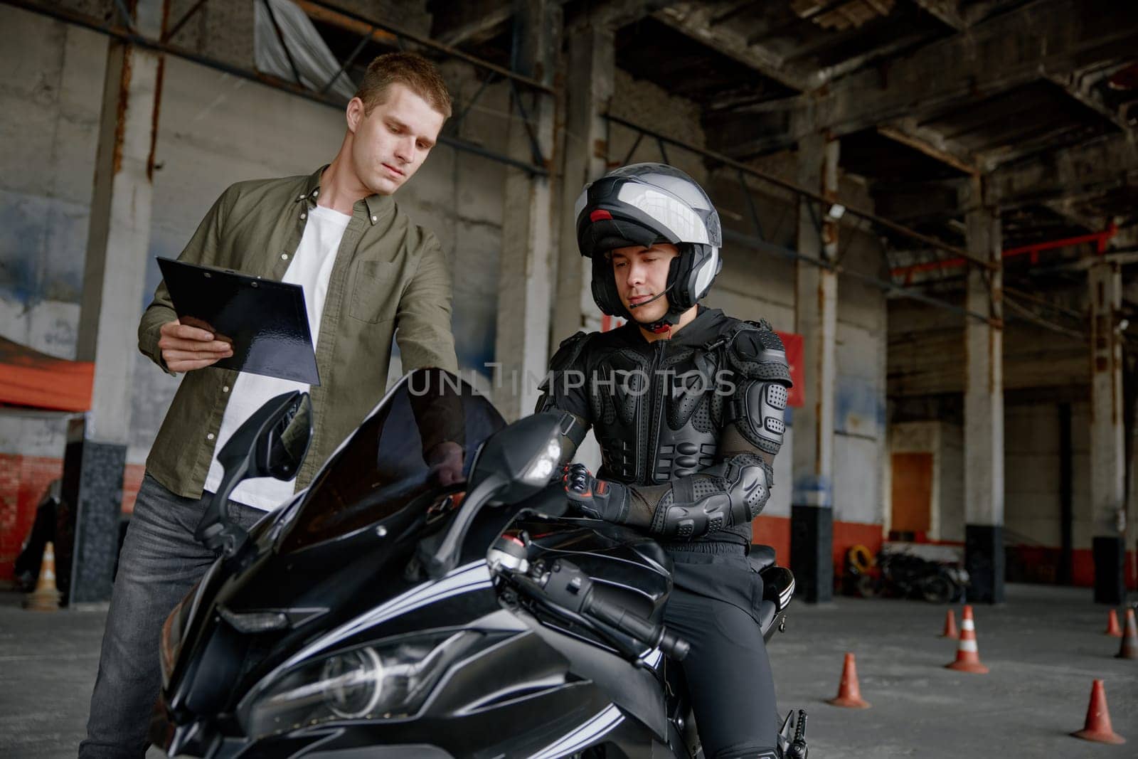 Personal lesson at motorcycle school concept. Male instructor teaching young biker explaining important things before start to move