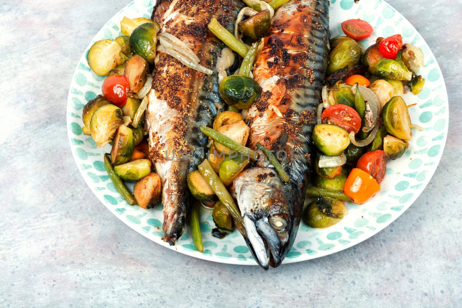 Plate with whole baked mackerel fish and tomatoes, cabbage and green beans
