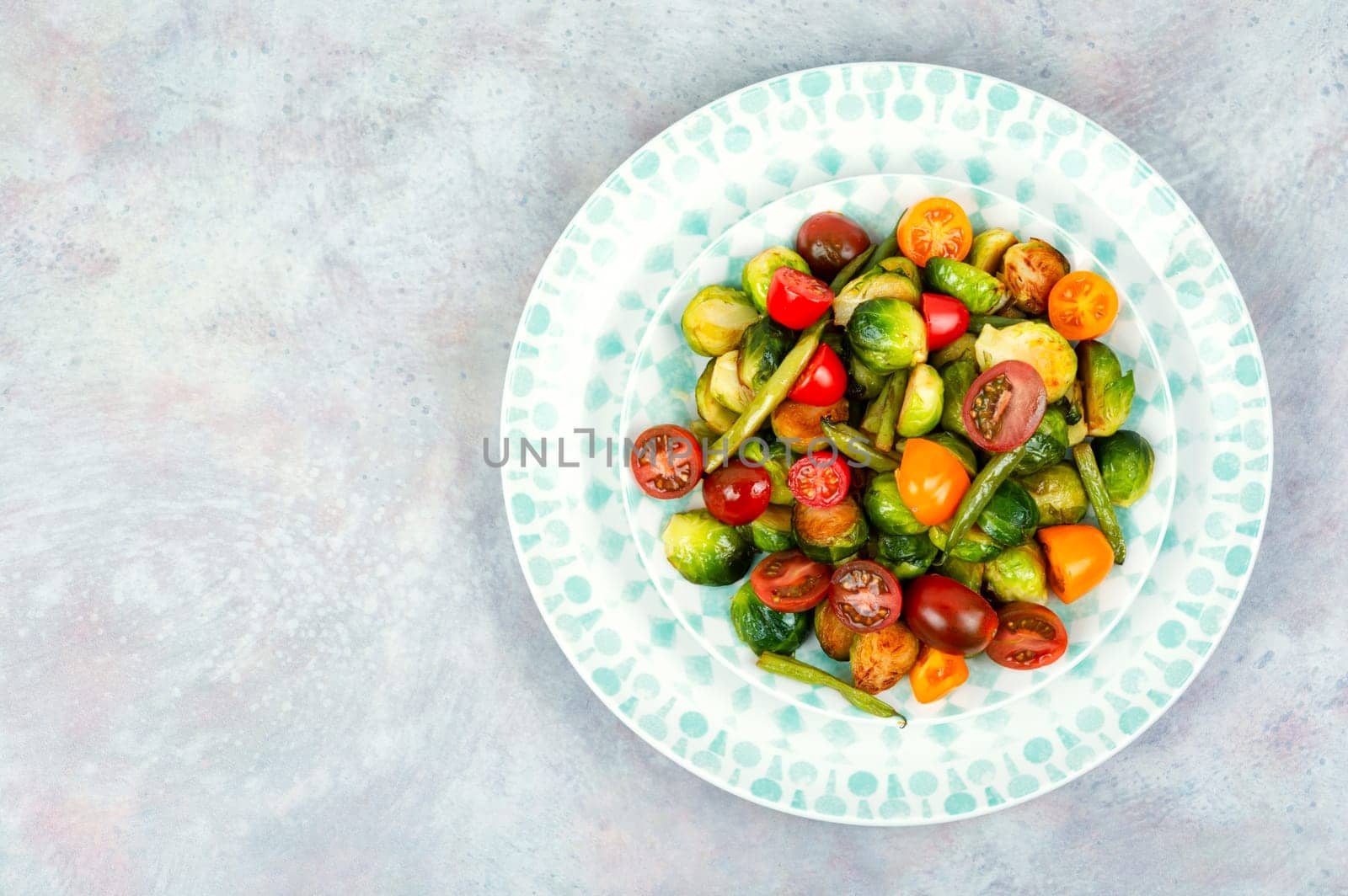 Vegetarian salad of roasted Brussels sprouts, tomatoes and green beans. Vegan food. Space for text.
