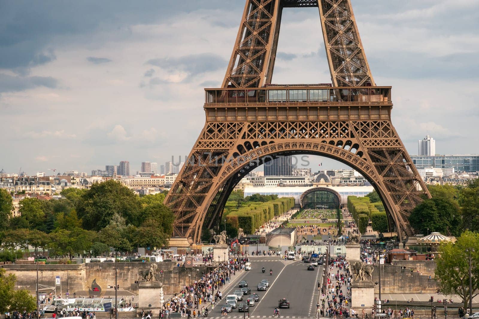 Paris, France - August 29 2023: Tourists under the Eiffel tower seen from Trocadero in a cloudy day. Photography taken in Paris.