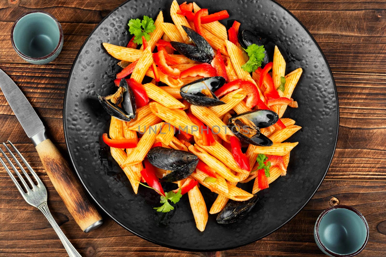 Macaroni with Atlantic mussels on a dark plate. Pasta with seafood. Noodles with mussels on wooden table. Top view.