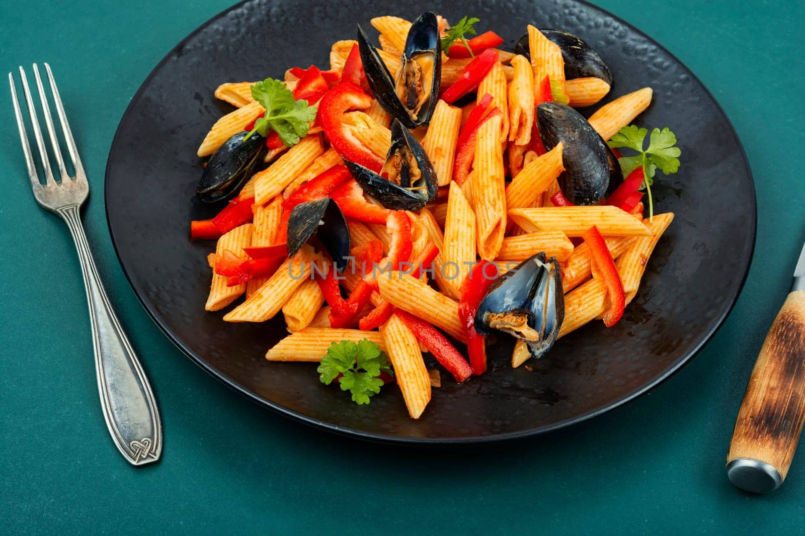 Macaroni with Atlantic mussels on a dark plate. Pasta with seafood. Noodles with mussels on wooden table. Top view.