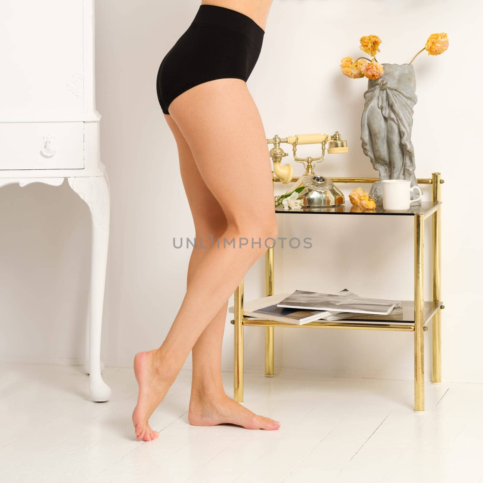 Side view of beautifully groomed naked female legs in high-waisted briefs