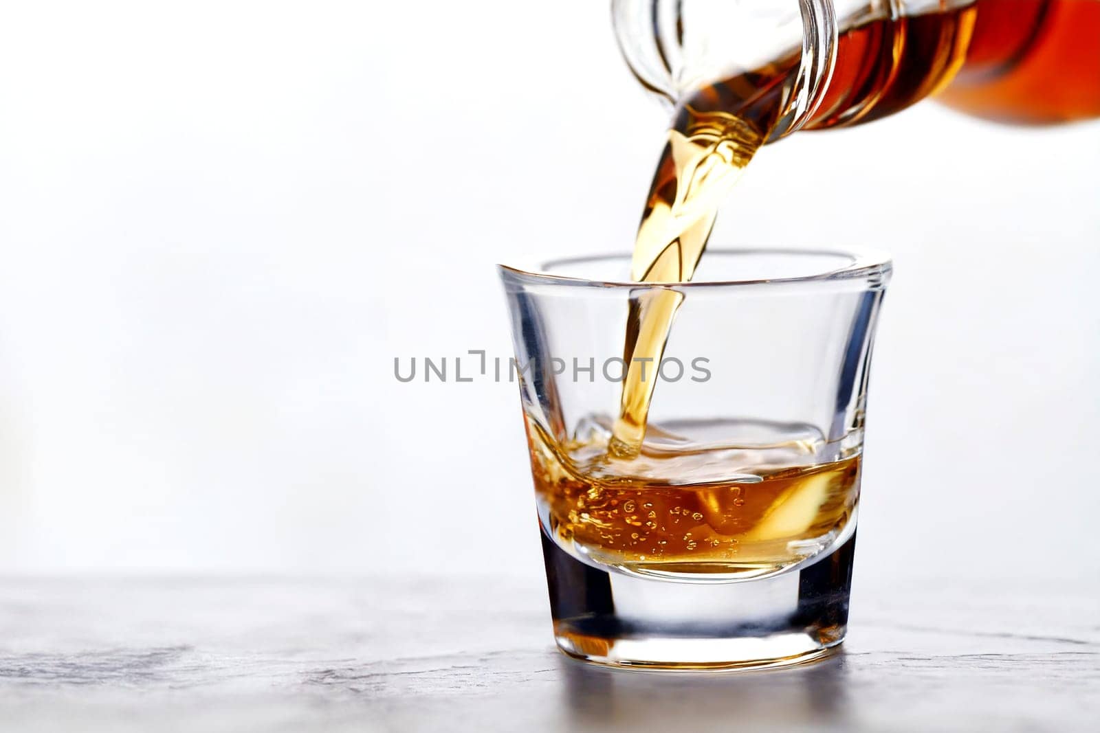 Whiskey being poured into a glass from a bottle on a white background. AI generated