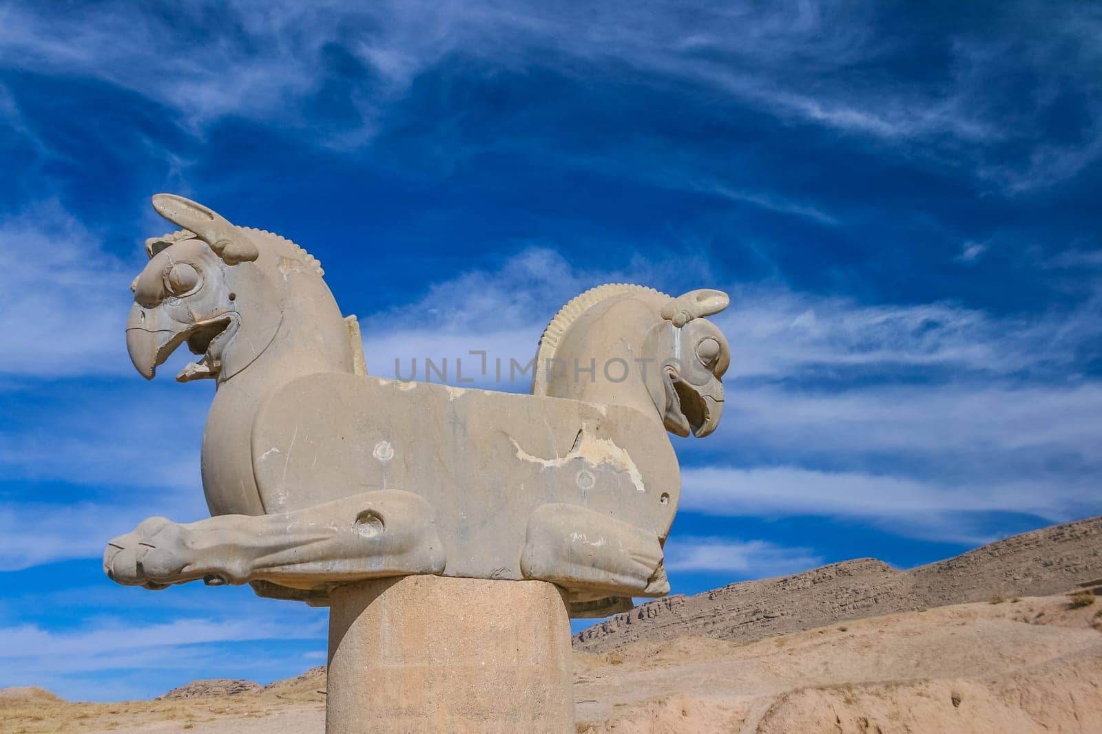 Fragment of stone column sculpture of a two-headed griffins in the ancient city of Persepolis, Iran. UNESCO World heritage site. On blue sky background