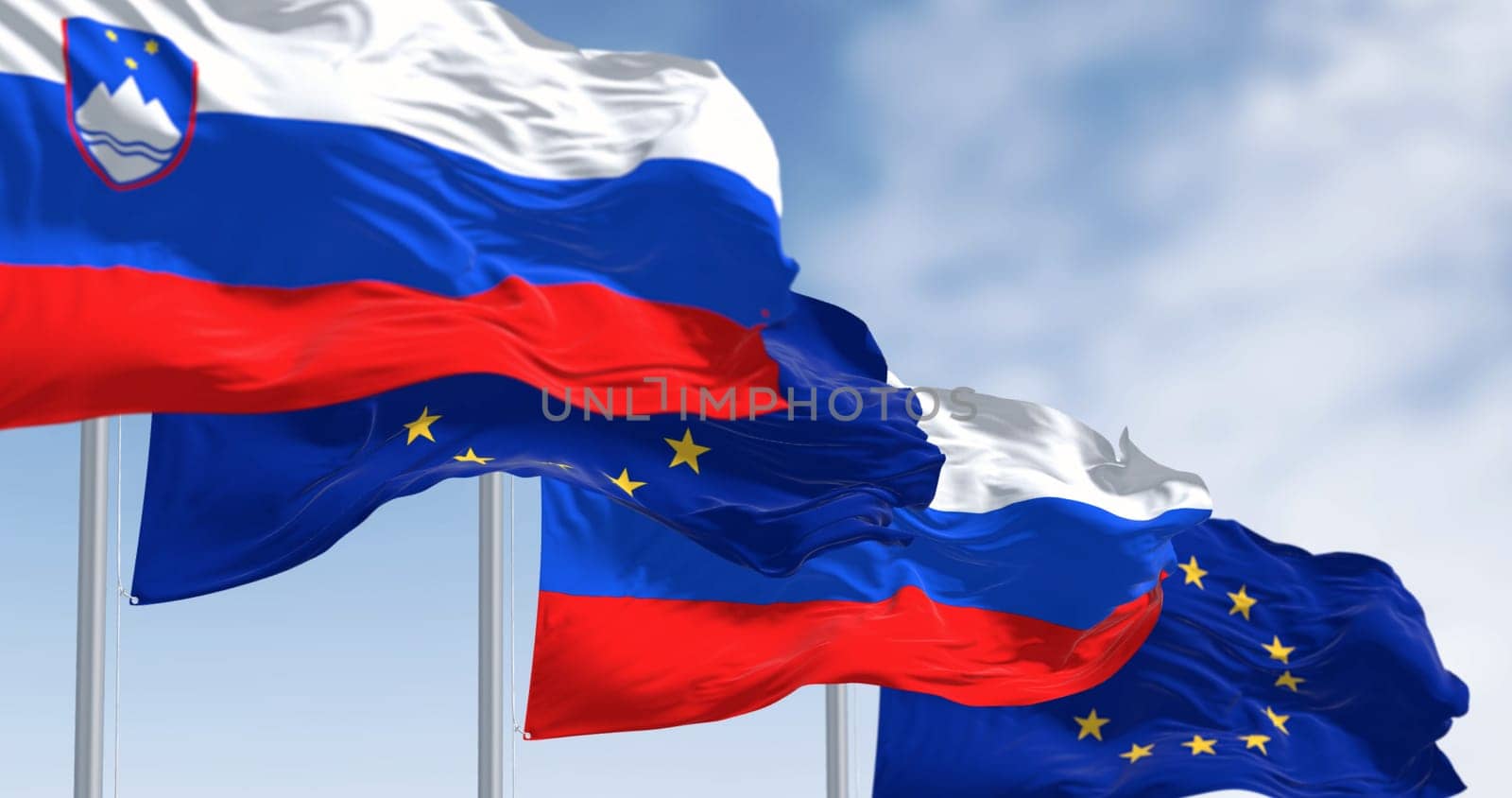 The flags of Slovenia and the European Union fluttering together on a clear day. Slovenia has been a member of the eurozone since January 1, 2007. 3D illustration render. Fluttering fabric
