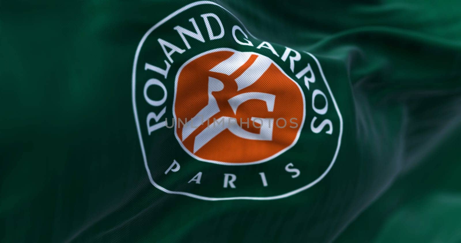 Paris, FR, Apr. 2023: Green flag with Roland Garros logo waving in the wind. French Open is a major tennis tournament scheduled in late May each year. Illustrative editorial 3d illustration render