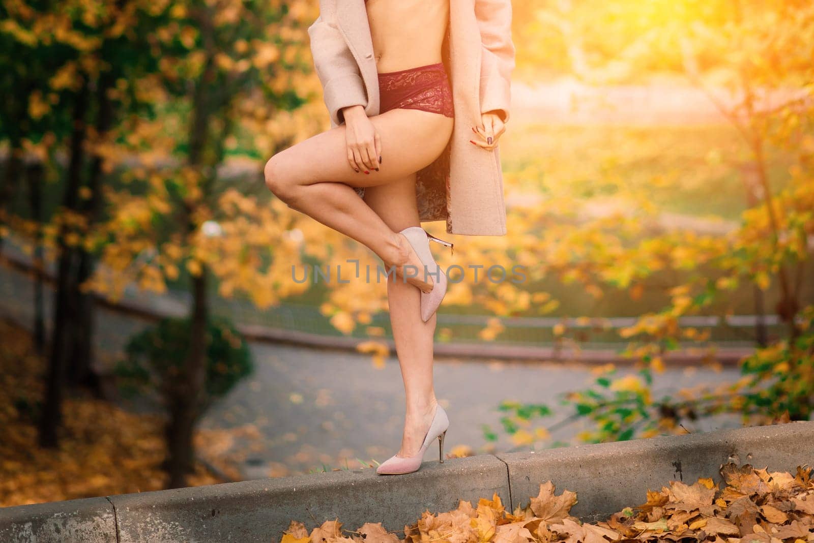 Fashion image of perfect long slim woman legs in an autumn park.