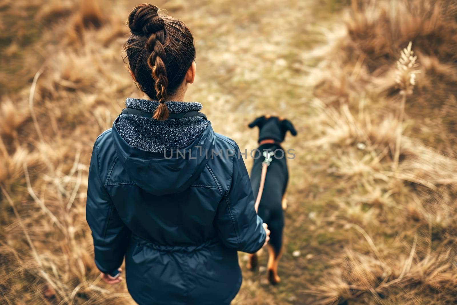 Young woman in a blue rain jacket walking a dog in a forest