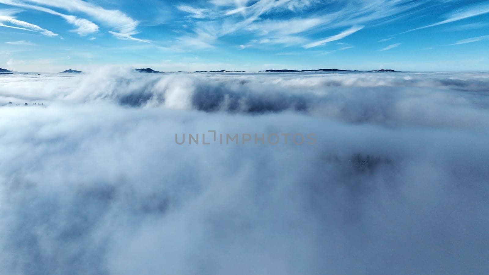 Drone shot in winter with fog in the valley and sun in the mountains