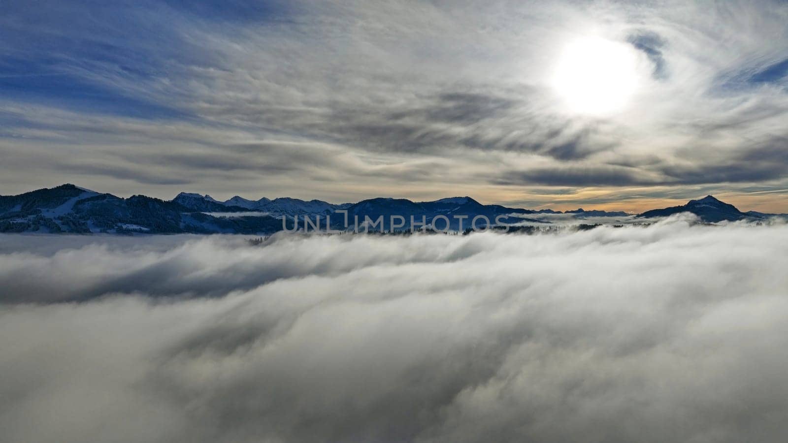 Drone shot in winter with fog in the valley and sun in the mountains