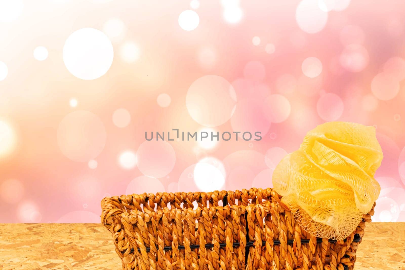 Empty wicker basket decorated with a yellow ribbon on table over abstract bright summer background. For your food and product display assembly. Copy space.