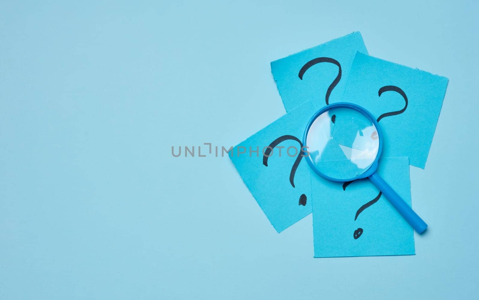 Drawn question marks on stickers and a magnifying glass, blue background. Searching for truth and answering questions