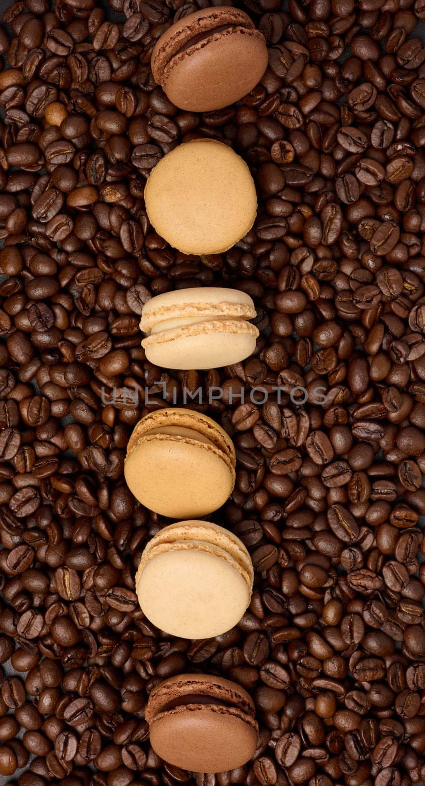 Multi-colored macarons on a background of coffee beans, top view