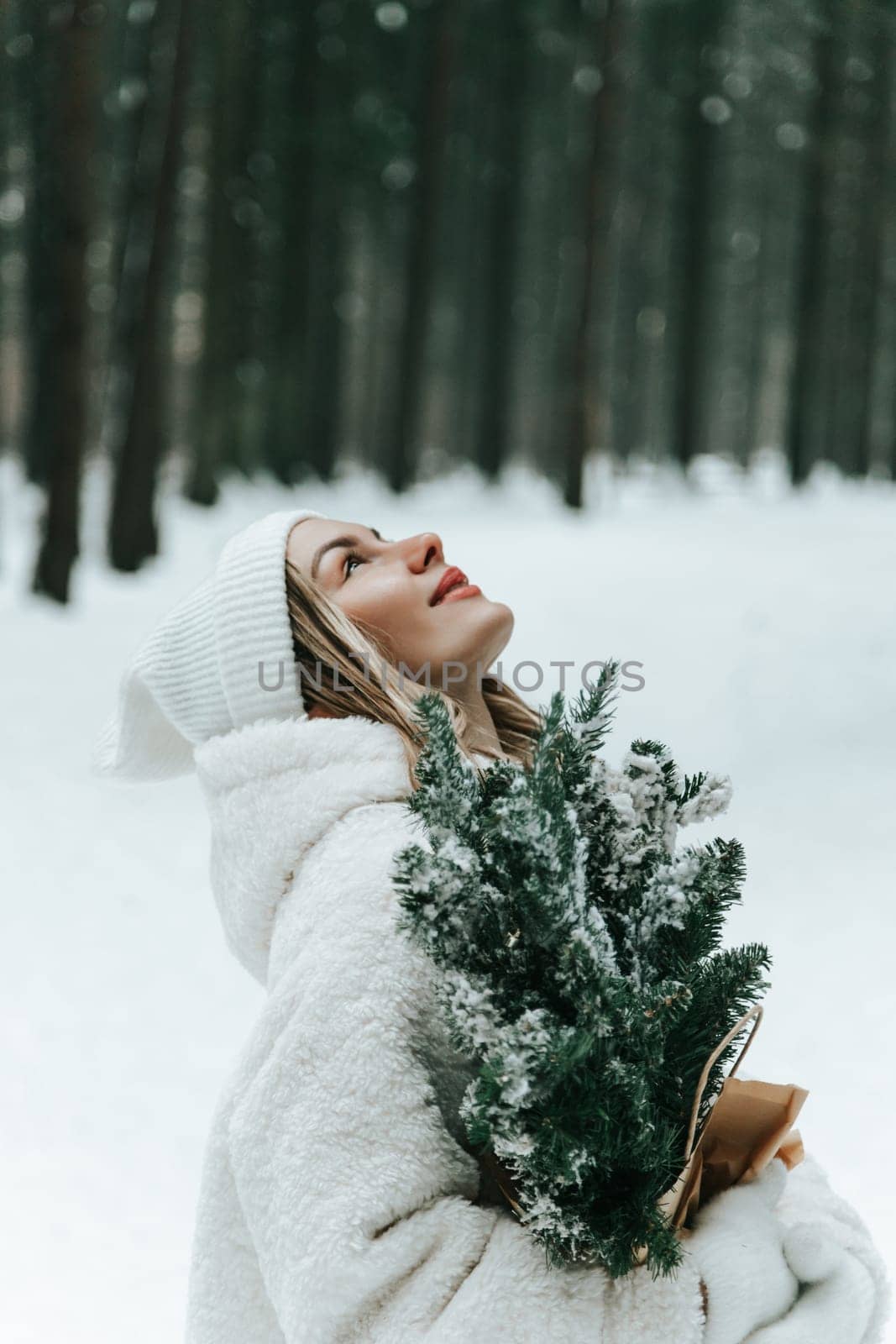 Happy young woman catching snowflakes with mouth in winter forest