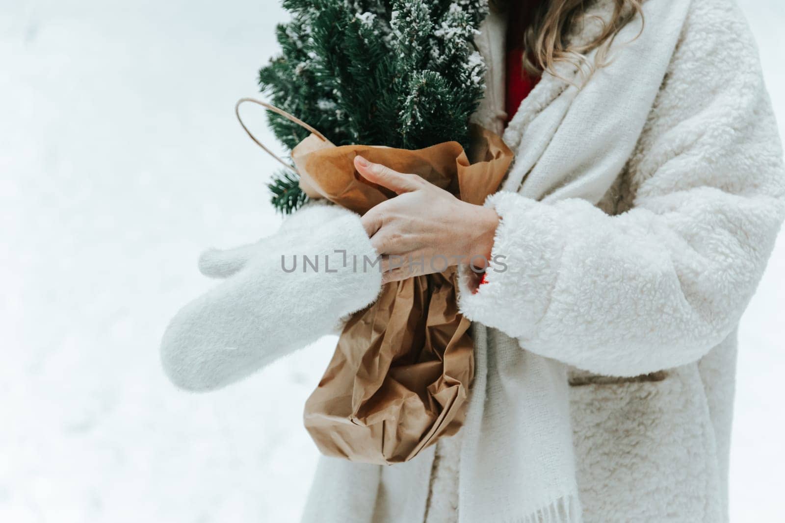Close up photo of female hands put on wool mittens outdoors, holding pine bouquet.