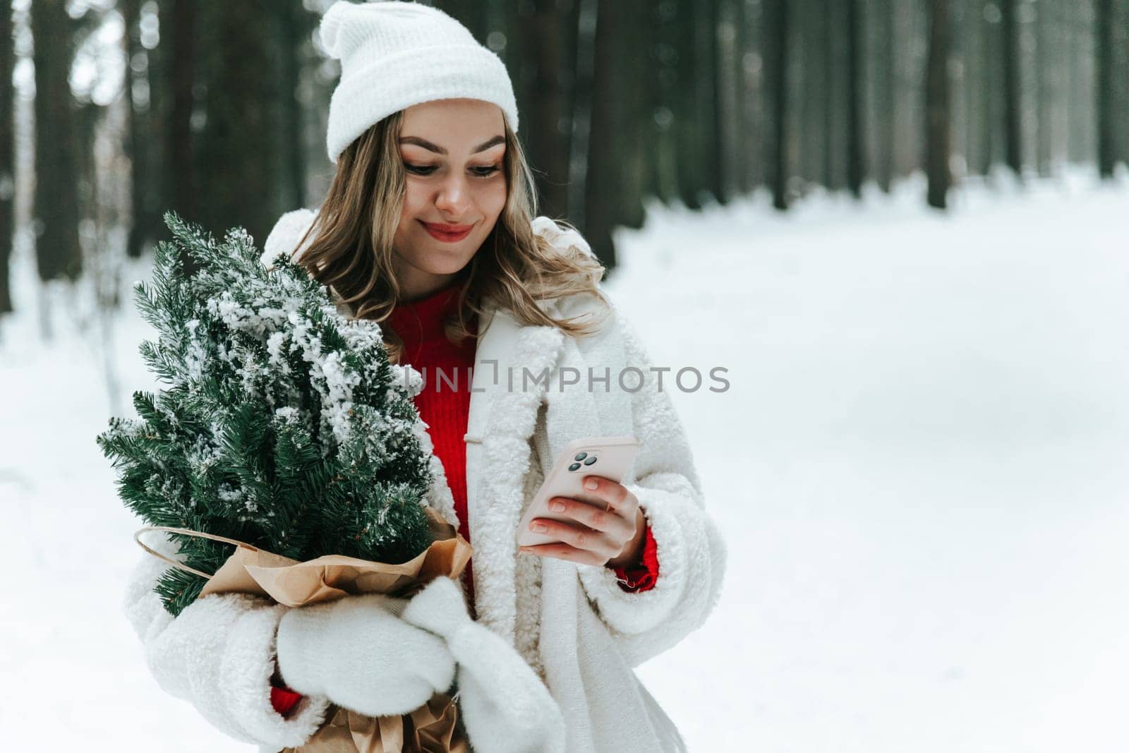 Young woman in a snowy forest with smartphone chatting online outdoors in the wild
