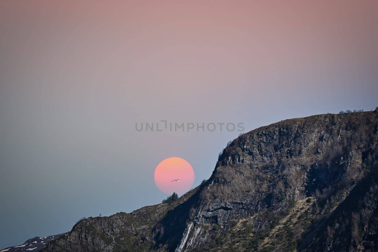 Westcap in Norway. Mountain that reaches into the fjord. Moon shining red behind the mountain. Landscape shot from Scandinavia
