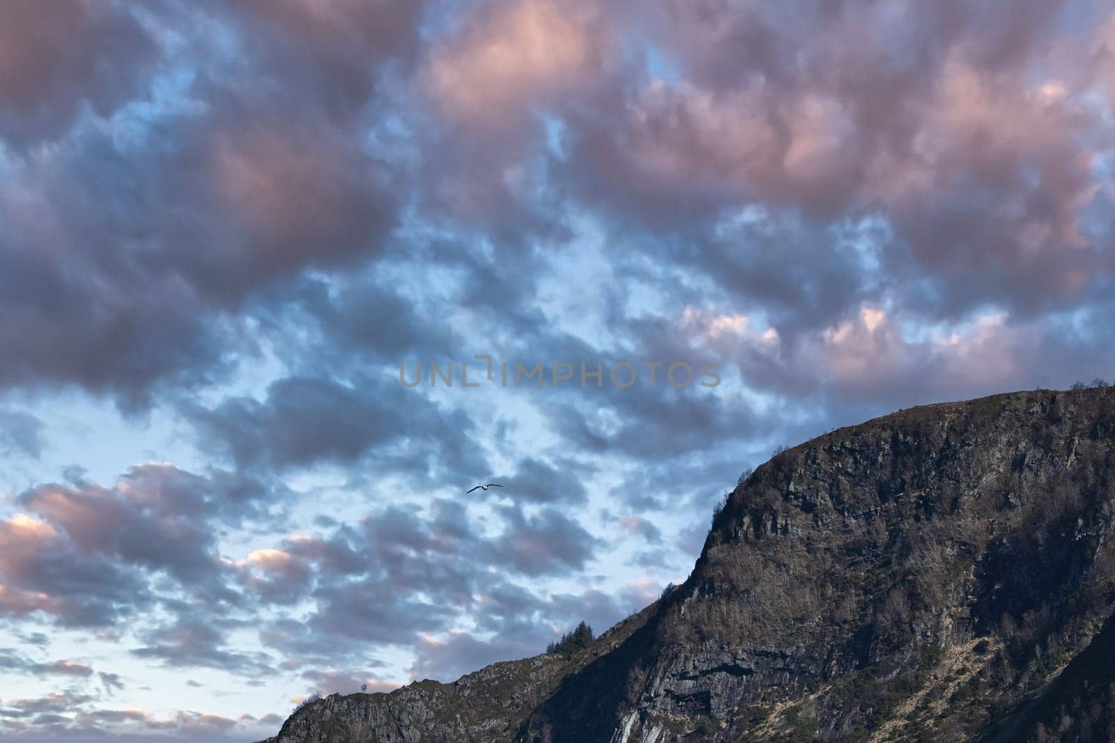 Westcap in Norway. Mountain that reaches into the fjord. Cloudy sky with clouds illuminated by the sun. Landscape shot from Scandinavia