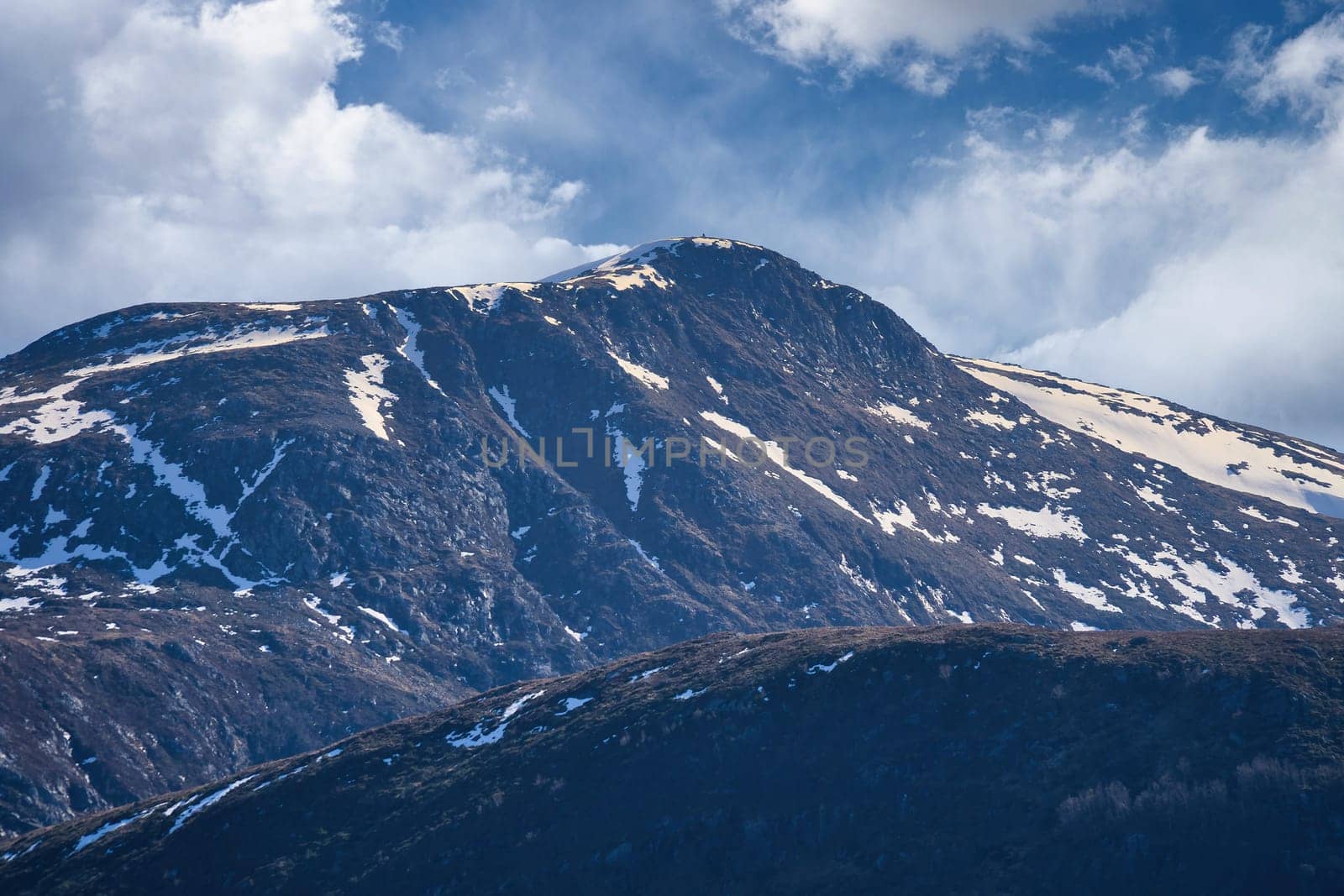 Western cap in Norway. Snow-covered mountain peaks. Very cloudy sky. Landscape shot from Scandinavia