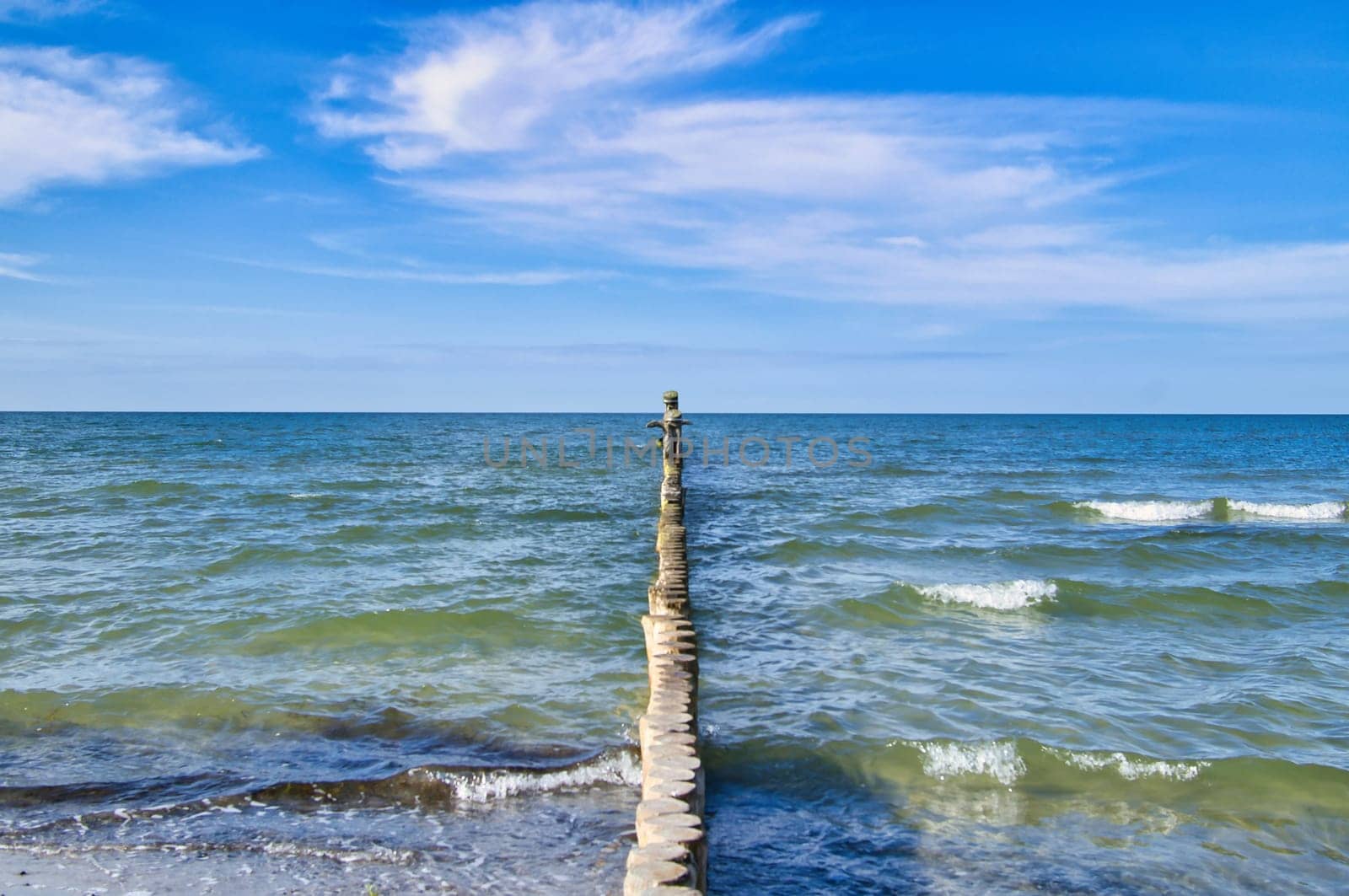 Groynes jut out into the Baltic Sea. Wooden trunks to protect the coast. Landscape from the sea